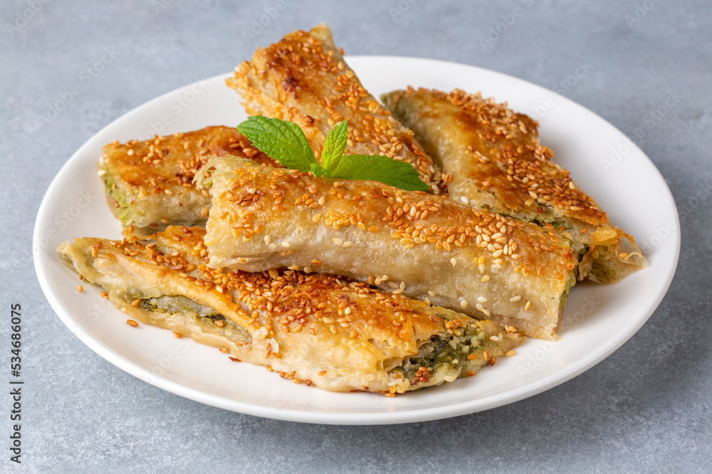 Greek cuisine dishes; spanakopita Sesame on handmade spinach feta cheese pie in the oven. Turkish name; ispanakli borek Greek cuisine dishes; spanakopita Sesame on handmade spinach feta cheese pie in the oven. Turkish name; ispanakli borek