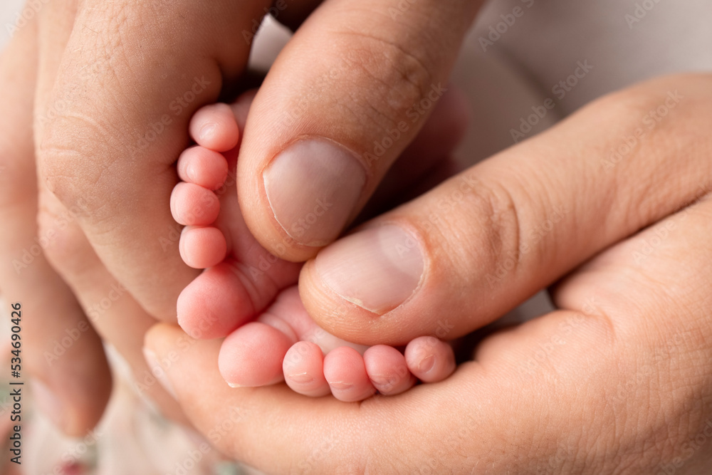 Mother and father are doing massage on her baby foot. Closeup baby feet in mother hands. Prevention of flat feet, development, muscle tone, dysplasia. Family, love, care, and health concepts. Mother and father are doing massage on her baby foot. Closeup baby feet in mother hands. Prevention of flat feet, development, muscle tone, dysplasia. Family, love, care, and health concepts.
