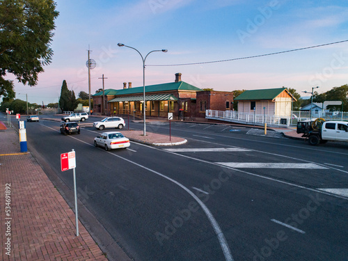 cars on road passing bus stop and train station in country town at dusk photo