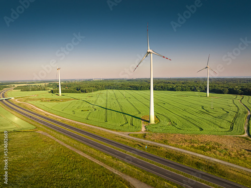 Wind turbines and green field near highway, aerial view
