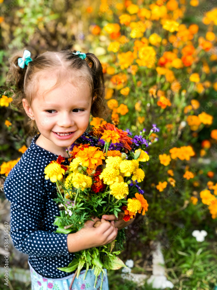 A little girl of European appearance poses with a huge bouquet of autumn flowers. Smiling child. The concept of a happy childhood A little girl of European appearance poses with a huge bouquet of autumn flowers. Smiling child. The concept of a happy childhood