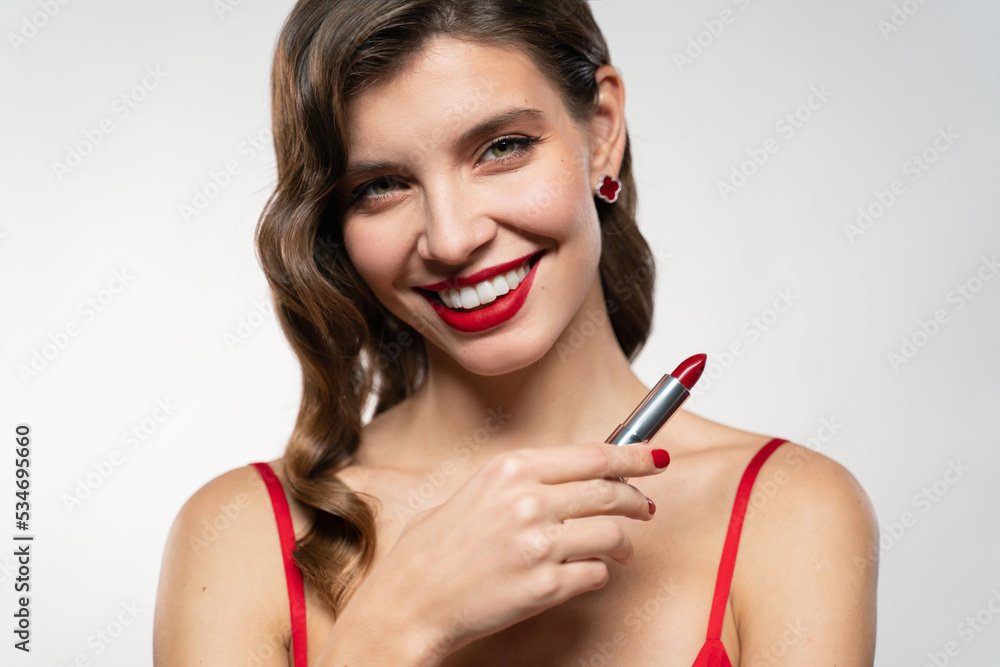 Close-up portrait of elegant woman with red lips and evening makeup holding lipstick Close-up portrait of elegant woman with red lips and evening makeup holding lipstick