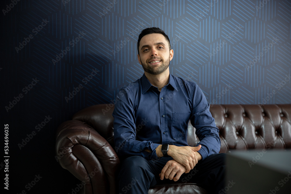 young businessman sitting on sofa looking forward young businessman sitting on sofa looking forward