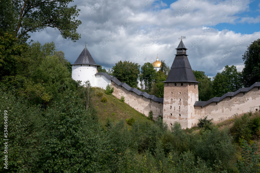 View of the outer wall of the Holy Dormition Pskov-Pechersk Monastery, the Tower of Upper Lattices, Khvostovsky Tower and St. Michael's Cathedral on a sunny summer day, Pechory, Pskov region, Russia