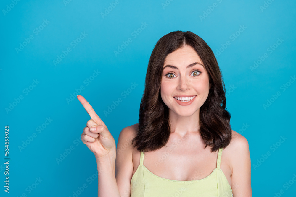 Portrait of pretty positive lady beaming smile direct finger empty space isolated on blue color background Portrait of pretty positive lady beaming smile direct finger empty space isolated on blue color background