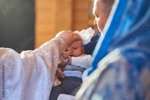 A small child at a baby christening ceremony in a church. the godfather holds a little boy in his arms. Baptism of a newborn. The sacrament of baptism. Child and God