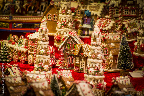 Advent Bazaar Stalls with glass, wooden, ceramic christmas souvenirs in a shop. Close up of festive decorations for tree in winter street night market during new year's holiday. Illuminated fair kiosk