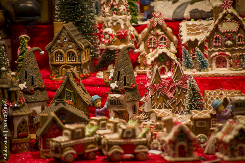 Advent Bazaar Stalls with glass, wooden, ceramic christmas souvenirs in a shop. Close up of festive decorations for tree in winter street night market during new year's holiday. Illuminated fair kiosk