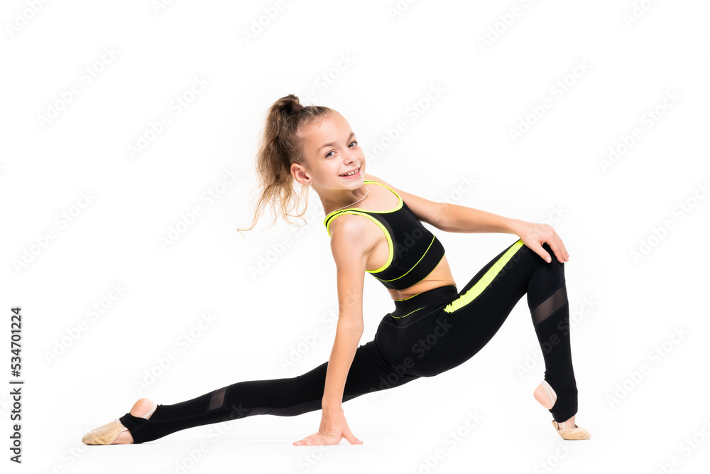 Flexible little girl gymnast in black sports gymnastic suit does acrobatic exercises isolated on a white background with space for text or logo. Sport, workout, fitness, yoga, active lifestyle concept