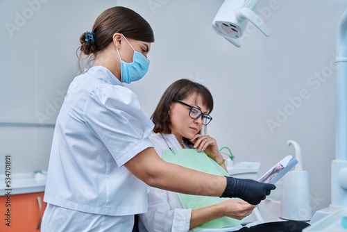 Female dentist talking to woman patient  discussing x-rays of teeth and jaws