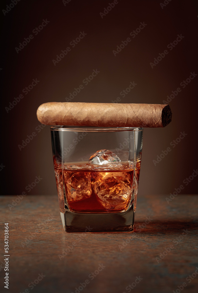 Whiskey with ice and cigar on a rusty background.