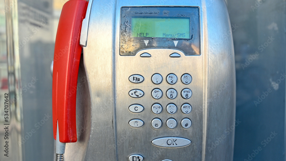 Old telephone booth dial numbers. Old Public phone booth on the street in the city. Keyboard with numbers and menu buttons on telephone. Old telephone booth dial numbers. Old Public phone booth on the street in the city. Keyboard with numbers and menu buttons on telephone.