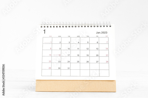January 2023 Desktop calendar for planners and reminders on a wooden table on a white background.