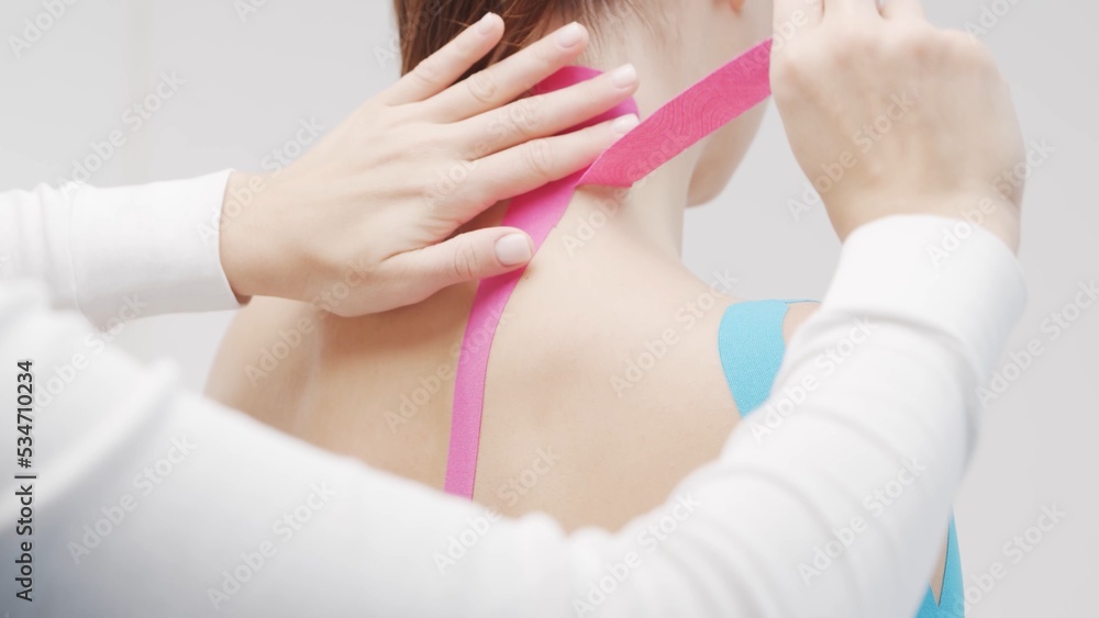 Fototapeta premium Therapist is applying tape to female body. Physiotherapy, kinesiology and recovery treatment.