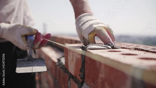 bricklayer lays red brick, masonry wall