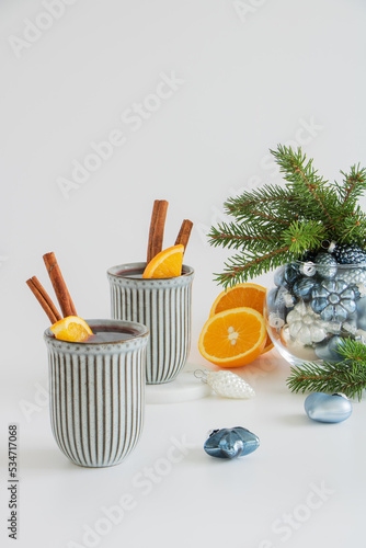 Christmas mulled wine. Punch, grog. Next to it are Christmas toys and fir branches in a glass vase on a light background.