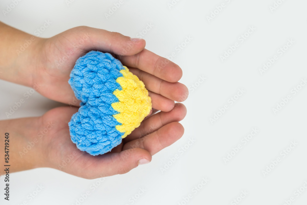 High angle view of children's hands holding a heart painted in the Ukrainian flag, hearts in hands on a white background. Patriotic concept. High angle view of children's hands holding a heart painted in the Ukrainian flag, hearts in hands on a white background. Patriotic concept.