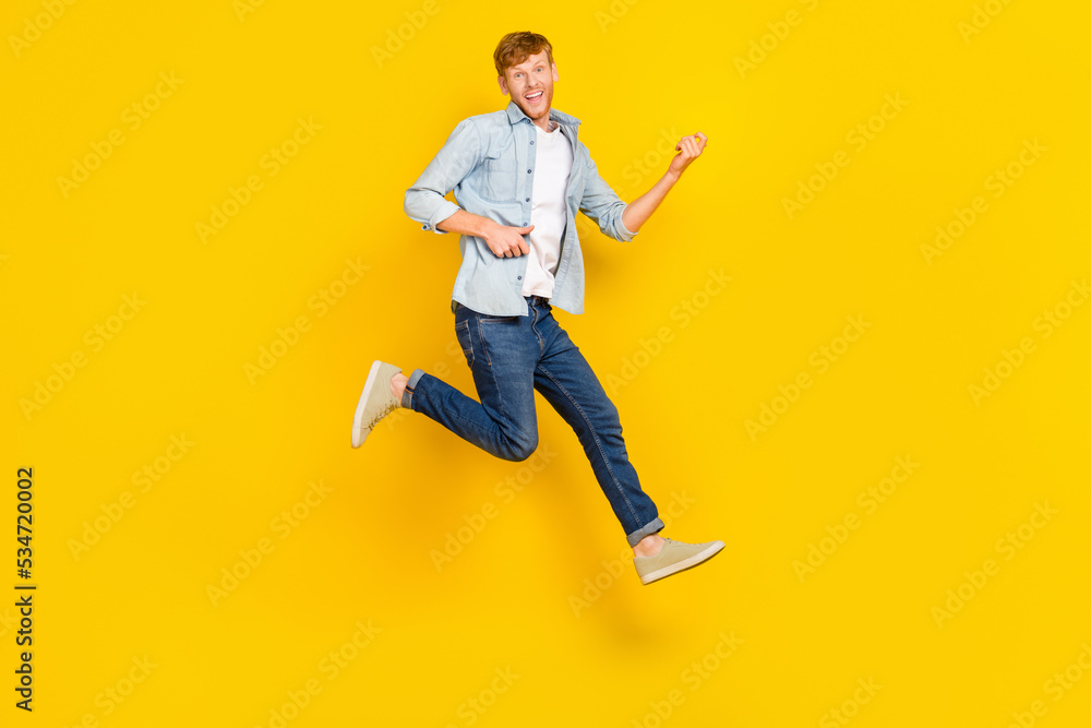 Full length photo of handsome guy red hair blue shirt jeans sneakers fooling playing imaginary guitar isolated on yellow color background