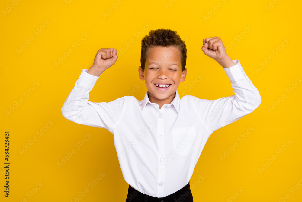 Fototapeta premium Photo of overjoied cheerful boy raise hand fist rejoice win contest competition eye closed isolated on yellow color background