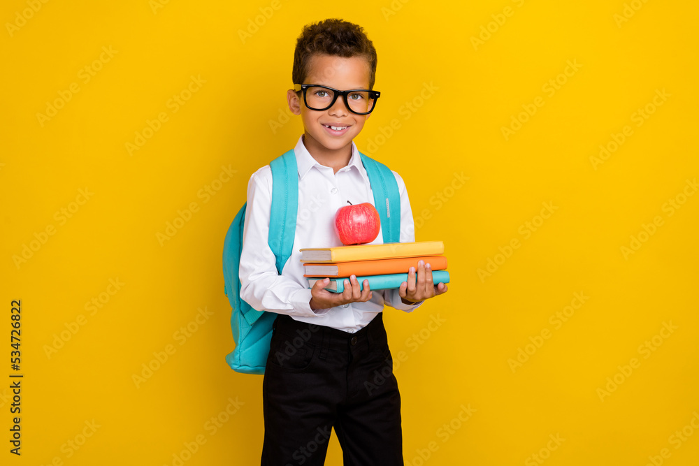 Photo of cheerful little person arms hold pile stack book literature fresh apple isolated on yellow color background