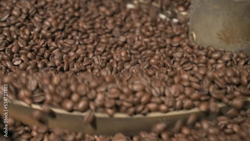 Close up brown coffee bean roasting in a coffee roasting machine with rotating metal arm in 4k.