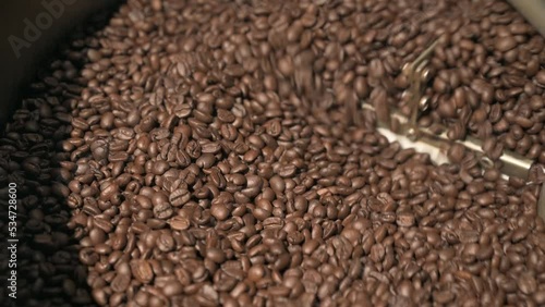 Close up brown coffee bean roasting in a coffee roasting machine with rotating metal arm in 4k.