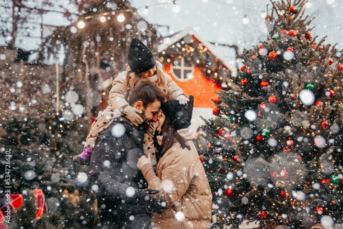 Photo of stylish family mommy daddy daughter piggyback happy positive smile look each other winter holliday outdoors