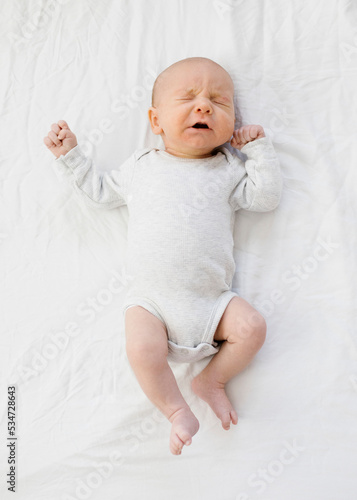 Overhead view of baby boy (0-1 months) sneezing on bed photo