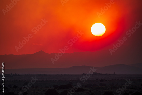 Usa, New Mexico, Santa Fe, Wildfire smoke and setting sun over desert landscape photo