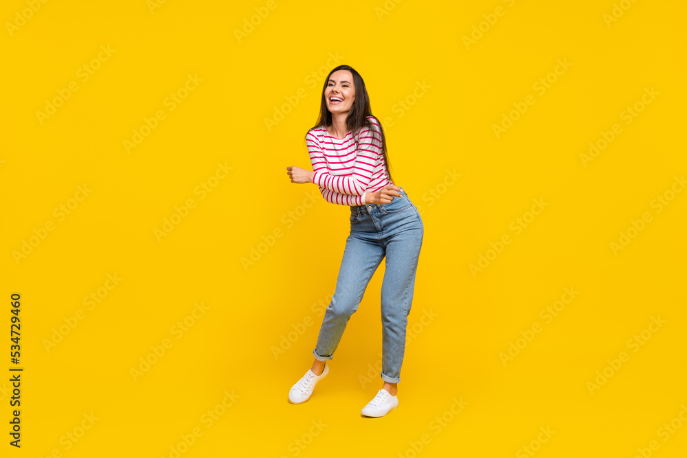 Full length photo of positive lady stylish striped clothes dance rejoice enjoy party look empty space isolated on yellow color background Full length photo of positive lady stylish striped clothes dance rejoice enjoy party look empty space isolated on yellow color background