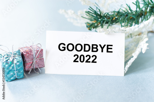 bye 2022 inscription on a card on a light background rdom two packed gifts with spruce branches