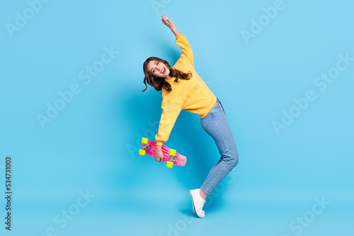 Full length photo of excited funky lady wear yellow sweater having fun holding longboard isolated blue color background © deagreez