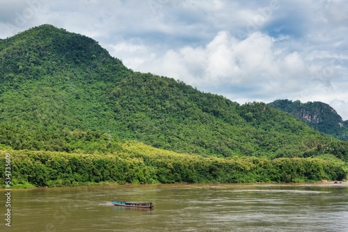 Long Boat travels down the Mekong River at Luang Prabang, beatiful river beetwen mountain forest