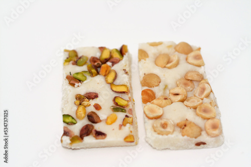 Arabian sweet candies of soft coconuts covered with pistachios and hazelnuts, Egyptian cultural desserts of prophet Muhammad birth celebration (mawlid halawa), festive Arabian candy and sweets photo