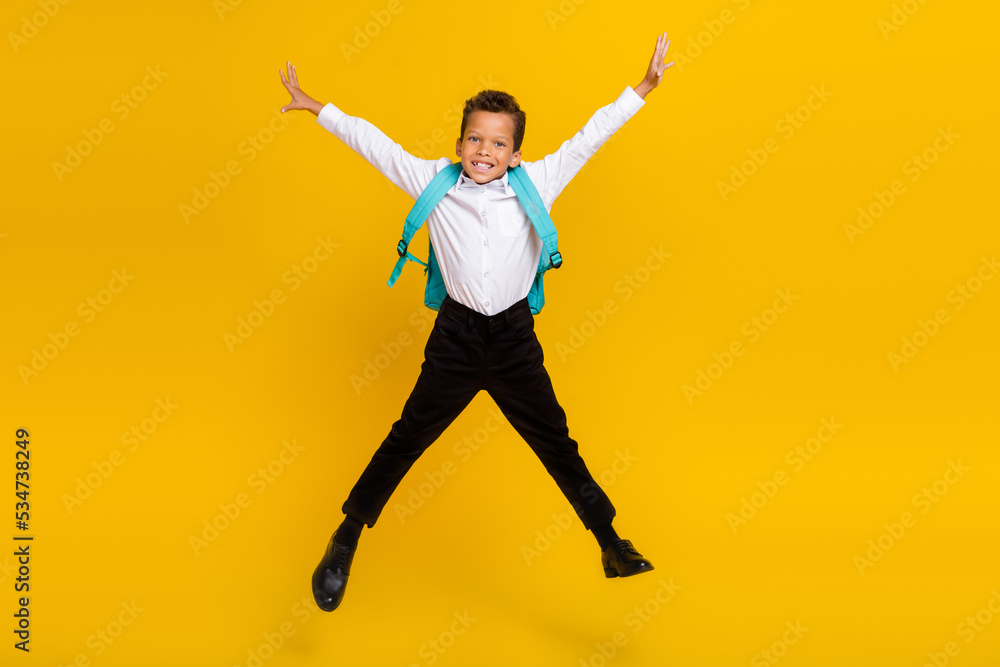 Full size photo of excited cheerful boy jumping carry backpack isolated on yellow color background