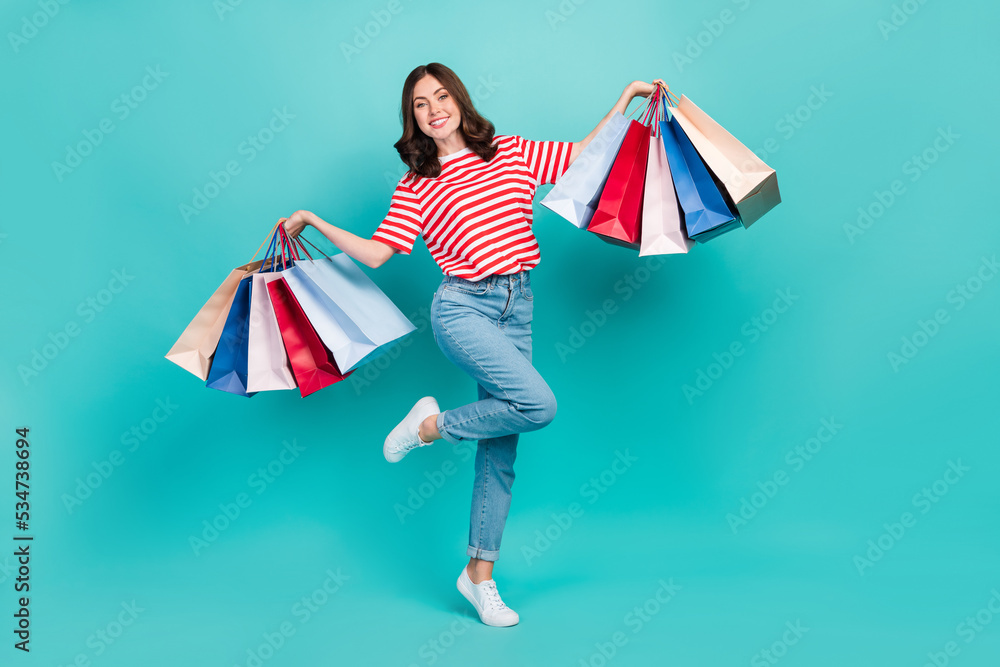 Full length photo of dreamy adorable girl dressed red t-shirt rising shoppers isolated teal color background Full length photo of dreamy adorable girl dressed red t-shirt rising shoppers isolated teal color background