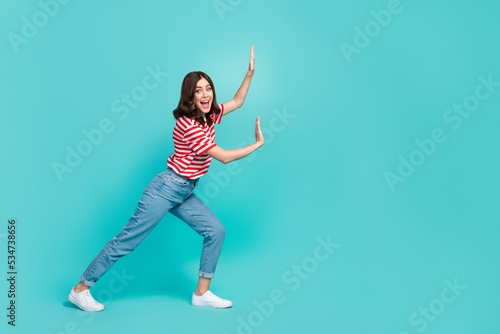 Full length photo of positive lady hold empty space push imaginary stone large product isolated on aquamarine color background photo