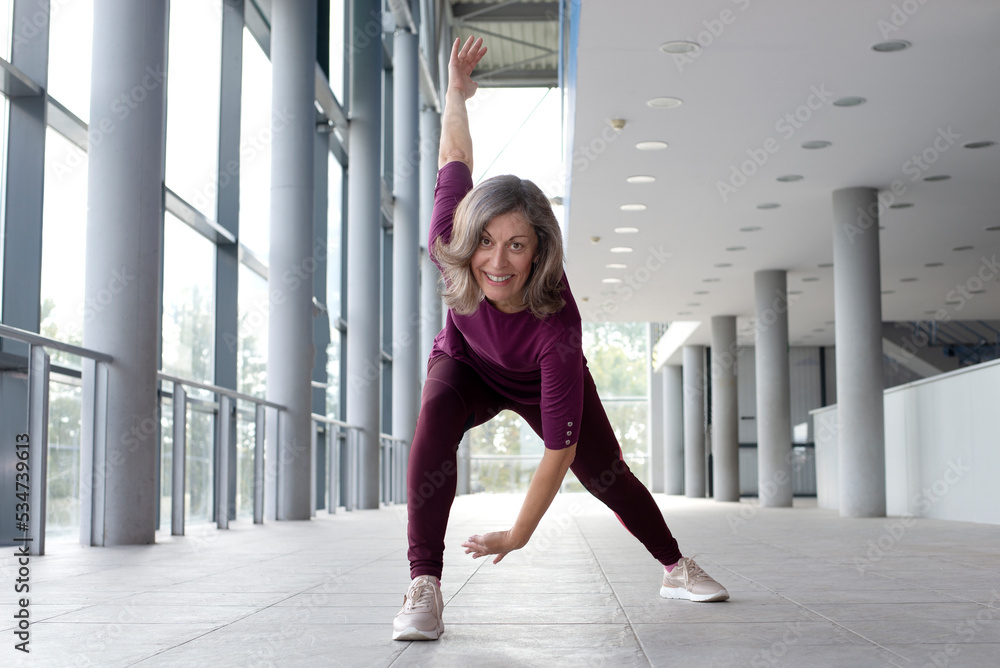 Mature woman in sports clothing stretching , Staying fit is one way to age with grace
