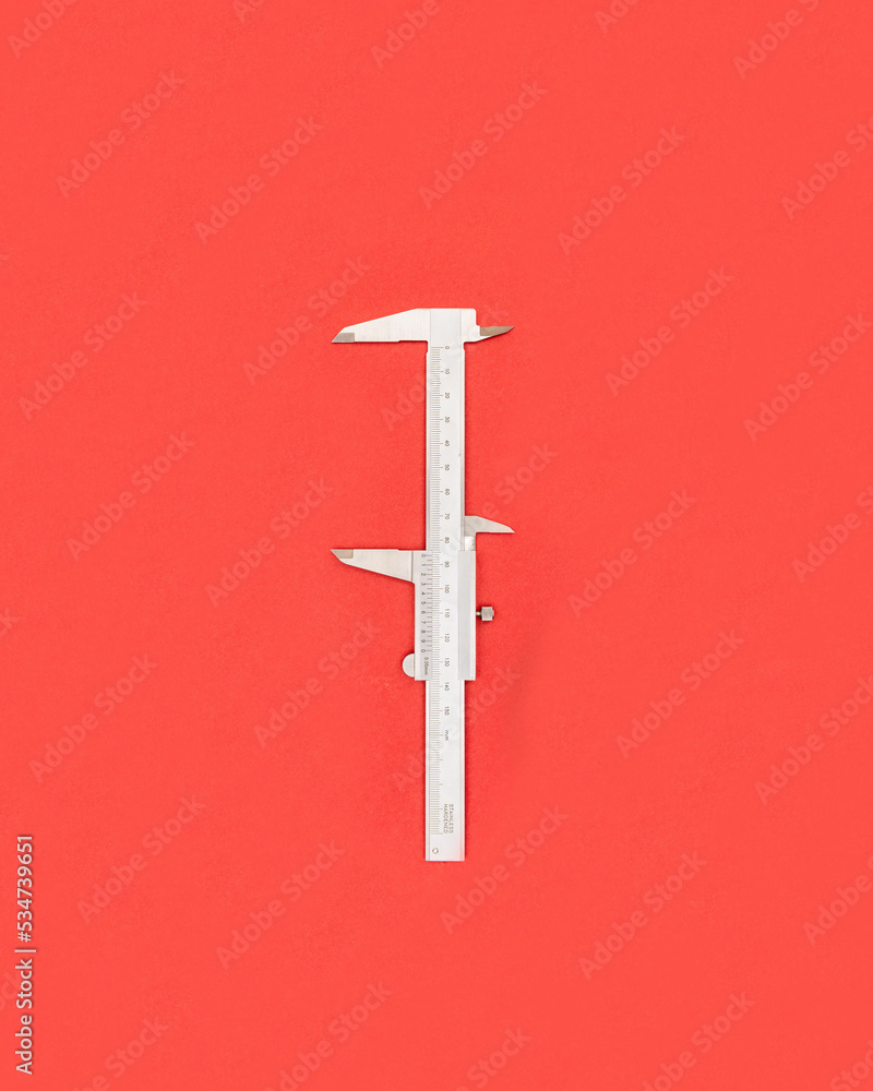 Wide opened metal caliper on the red background with copy space Wide opened metal caliper on the red background with copy space