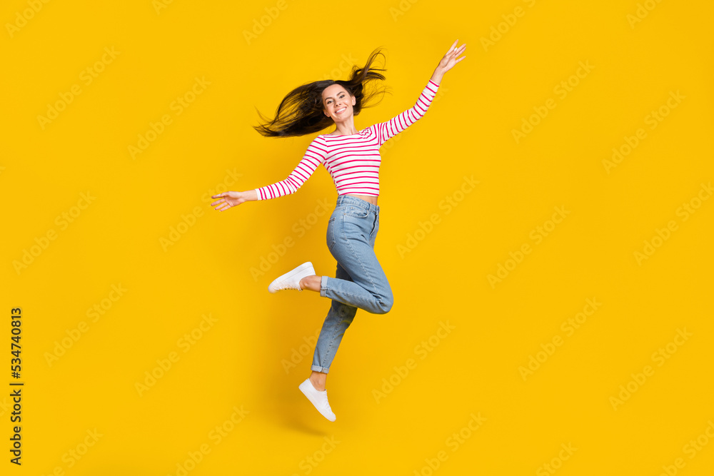Full length photo of cheerful gorgeous girl wear striped long sleeve jeans arms plane wings flying isolated on yellow color background - obrazy, fototapety, plakaty 