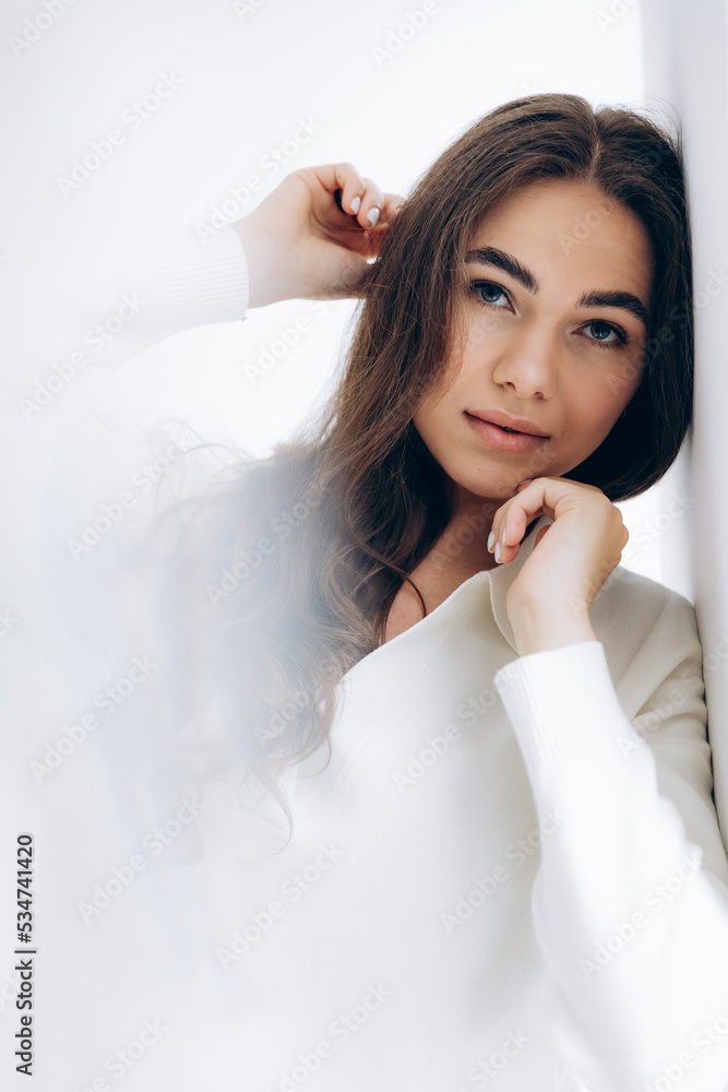 29.04.22 Kyiv, Ukraine: stylish portrait of a young woman posing for a photo on a white background studio cyclora with natural daylight from the window 29.04.22 Kyiv, Ukraine: stylish portrait of a young woman posing for a photo on a white background studio cyclora with natural daylight from the window