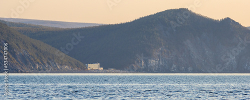 Morning panorama of the sea coast. View of the bay and mountains. In the distance on the shore is the building of the recreation center. Gertner Bay, Sea of Okhotsk, Magadan Region, Russian Far East. photo