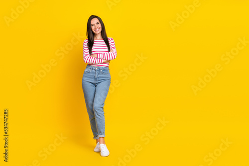 Full length photo of cute funny lady arm folded wear striped outfit stand empty space isolated on yellow color background