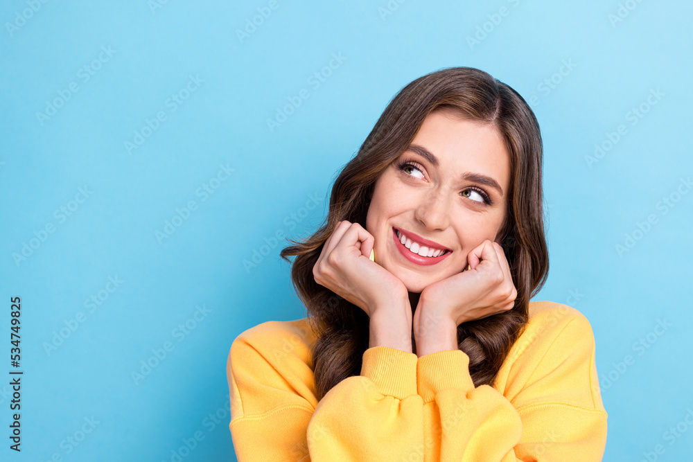 Closeup photo of young positive pretty gorgeous lady dreamy look empty space wear yellow sweater touch cheeks new advert isolated on blue color background Closeup photo of young positive pretty gorgeous lady dreamy look empty space wear yellow sweater touch cheeks new advert isolated on blue color background
