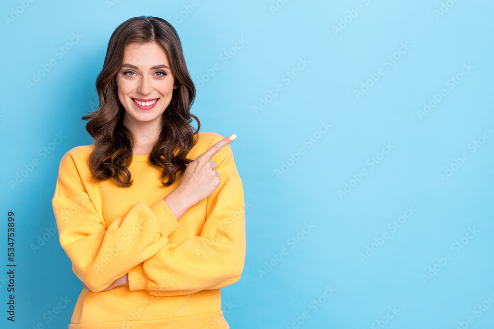 Closeup photo of young pretty nice gorgeous girl wear yellow pullover finger point empty space recommend product ad isolated on blue color background
