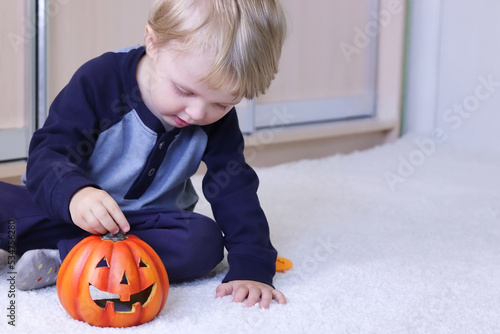 Defocused child playing with halloween pumpkins. Copy space - Halloween autumn holiday concept, halloween party, home decoration, fun, curiosity