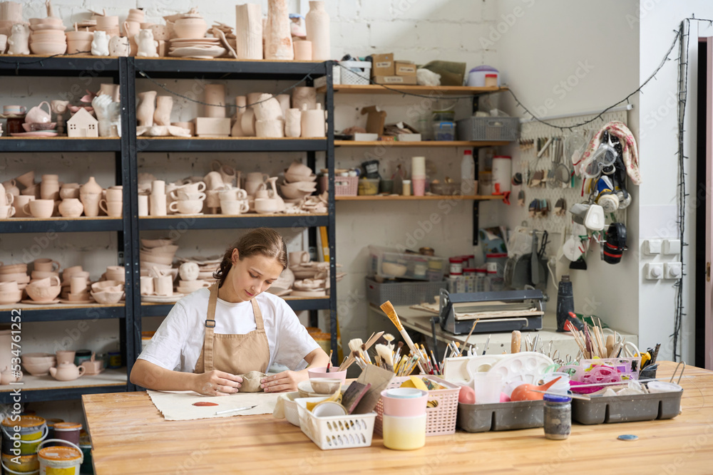 Young female student practicing in a pottery studio - obrazy, fototapety, plakaty 