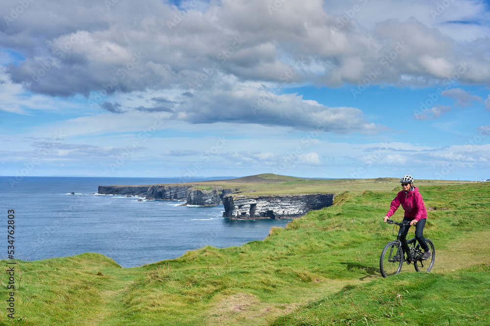 nice senior woman on mountain bike, cycling on the cliffs of Cnoc an Daimh, Kilgalligan the northern part of the Republic of Ireland