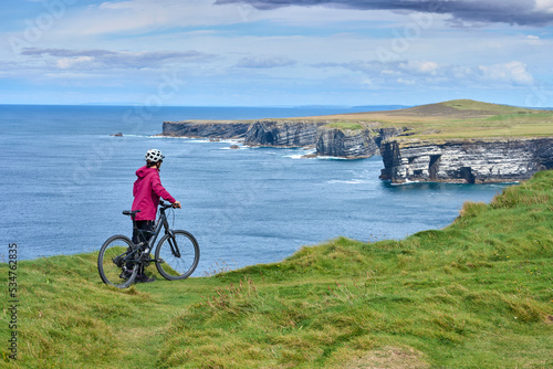 nice senior woman on mountain bike, cycling on the cliffs of Dunmore Head near Kilballyowen , County Limerick in the southwestern part of the Republik of Ireland photo