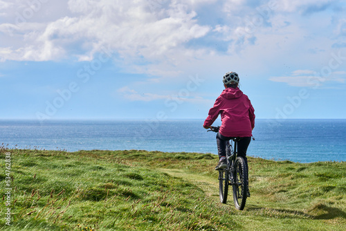 Fototapeta Naklejka Na Ścianę i Meble -  nice senior woman on mountain bike, cycling on the cliffs of Dunmore Head near Kilballyowen , County Limerick in the southwestern part of the Republik of Ireland